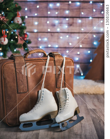 Women's skates next to an old leather suitcase and a Christmas tree. Christmas Decorations Women's skates next to an old leather suitcase and a Christmas tree. Christmas Decorations 130816663