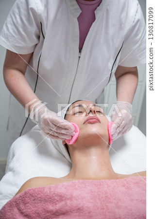 Beautician performing facial skincare treatment for female client in beauty salon Beautician performing facial skincare treatment for female client in beauty salon 130817099