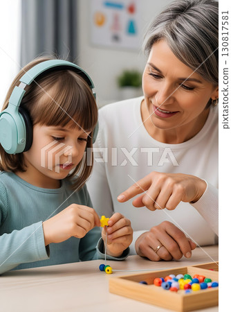 Autistic child girl in occupational therapy with turquoise headphones threading colorful beads for fine motor skills autism spectrum learning and inclusion awareness 130817581