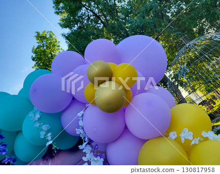 On a sunny day, festive inflatable blue, yellow, and lilac balloons in a children's park 130817958