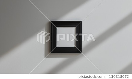 Minimalistic still life photography of a black frame with a solid white center on a light gray wall with shadows 130818072