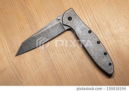 Detailed view of a modern gray steel folding knife half opened, top view 130818104