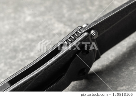 Detailed macro photo of a modern black folding knife with textured handle Detailed macro photo of a modern black folding knife with textured handle 130818106