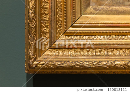 Corner of a vintage gilded frame is on green wall, wooden carving details Corner of a vintage gilded frame is on green wall, wooden carving details 130818111