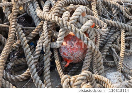 Ropes intricately tangled around a weathered red buoy, close up photo Ropes intricately tangled around a weathered red buoy, close up photo 130818114