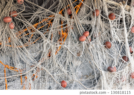 Dry fishing nets intertwined with orange ropes and buoyant floats 130818115