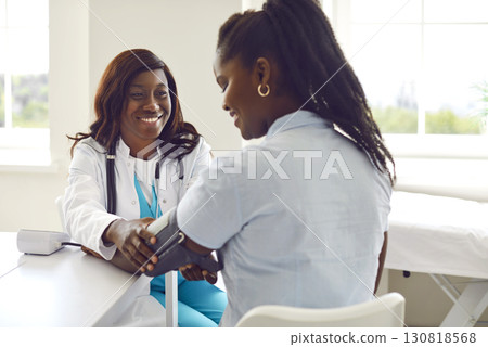Smiling woman doctor therapist measuring blood pressure of a patient in medical office. 130818568