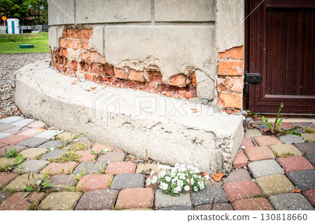 Crumbling facade plaster revealing old damaged brick wall 130818660