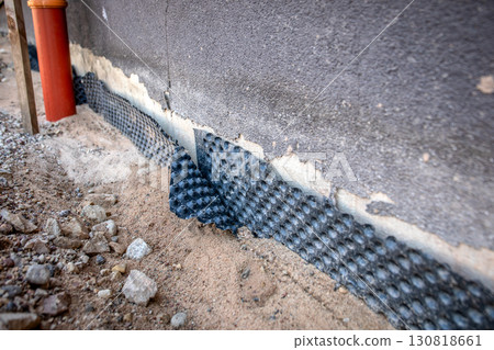 Close-up view of damaged foundation waterproofing membrane during construction Close-up view of damaged foundation waterproofing membrane during construction 130818661