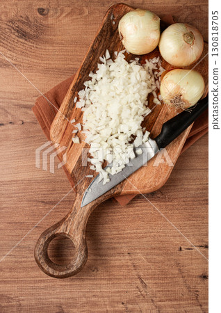 finely chopped onion on a chopping board with a knife, wooden table, top view, no people, 130818705
