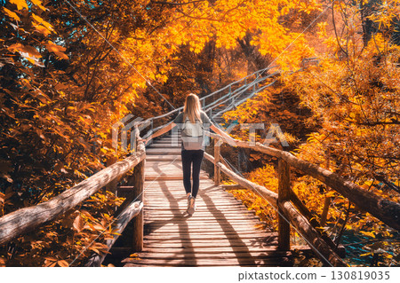 Woman with backpack walking on wooden path. Waterfalls in autumn 130819035