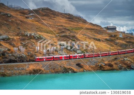 Aerial view of red train near alpine mountain lake and cloudy sky Aerial view of red train near alpine mountain lake and cloudy sky 130819038