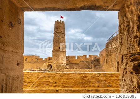 View through arch to the watch tower with tunisian flag on the top of Ribat of Monastir under cloudy skies, Monastir, Monastir Governorate, Tunisia View through arch to the watch tower with tunisian flag on the top of Ribat of Monastir under cloudy skies, Monastir, Monastir Governorate, Tunisia 130819395