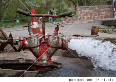 Draining water from building plumbing system. Water flows from faucet and pipe Draining water from building plumbing system. Water flows from faucet and pipe 130819415