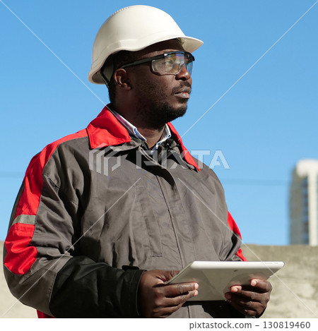 African american worker with tablet computer stands at construction site 130819460
