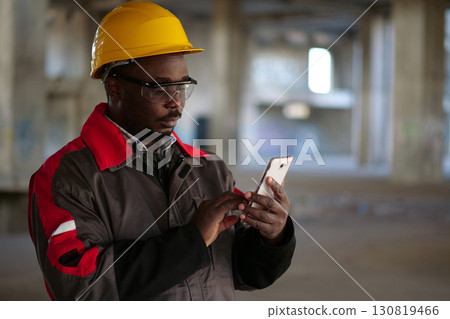 African american workman with smartphone at construction site 130819466