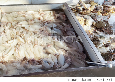 Fresh catching squid and crabs is arrayed in neat rows at a fish market, showcasing the raw, unadorned beauty of seafood waiting to be transformed into culinary delights Fresh catching squid and crabs is arrayed in neat rows at a fish market, showcasing the raw, unadorned beauty of seafood waiting to be transformed into culinary delights 130819651