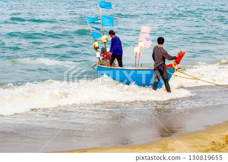Blue boat and fishermen at sea coast, embodying the spirit of maritime labor and the bountiful ocean, ideal for themes of fishing, tradition, wild freshly catching seafood and nature's gifts 130819655