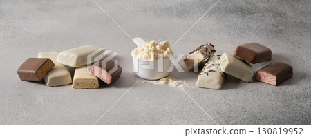 Protein bars with various coatings and sprinkles scoop of protein powder on gray background. Fitness nutrition. Close up. 130819952