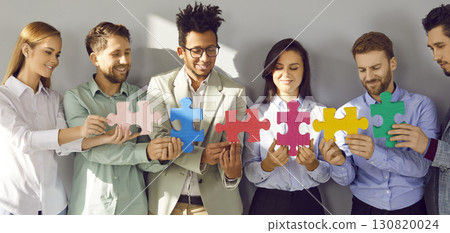 Banner with team of happy young diverse business people holding colorful jigsaw puzzle pieces Banner with team of happy young diverse business people holding colorful jigsaw puzzle pieces 130820024