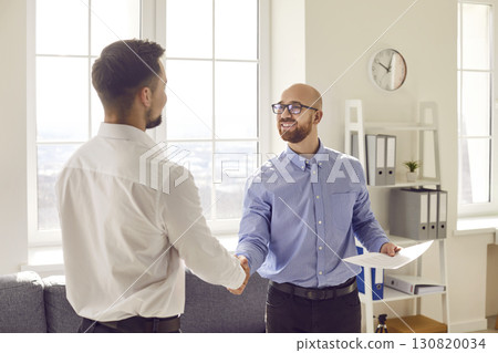 Two business men standing in office making deal shaking hands celebrating business achievement. Two business men standing in office making deal shaking hands celebrating business achievement. 130820034