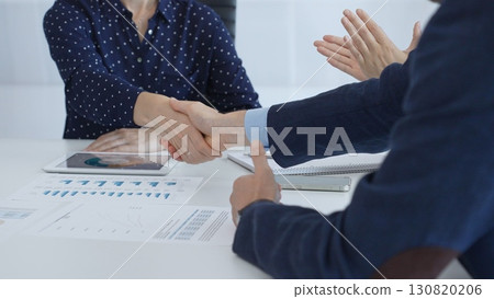 Business people shaking hands at a meeting, celebrating successful negotiations and signing a contract, with documents, digital tablet, and smartphone on the table. Handshake concept Business people shaking hands at a meeting, celebrating successful negotiations and signing a contract, with documents, digital tablet, and smartphone on the table. Handshake concept 130820206