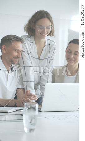 Professional team reviewing project data on laptop, working together in modern office environment, collaborating with focused corporate energy Professional team reviewing project data on laptop, working together in modern office environment, collaborating with focused corporate energy 130820237