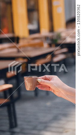 Hand holding a coffee cup in a cozy cafe with blurred background. 130820362