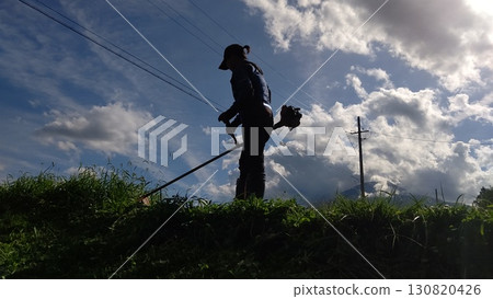 一名婦女在農場道路上割草 一名婦女在農場道路上割草 130820426