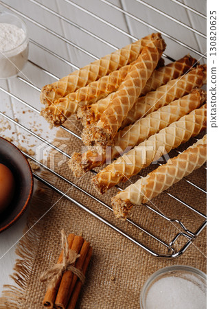 Crispy homemade waffle rolls with nut filling on cooling rack, rustic background Crispy homemade waffle rolls with nut filling on cooling rack, rustic background 130820625