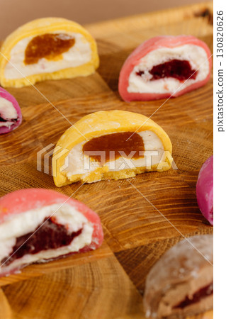 Assorted colorful mochi ice cream halves on wooden board, close-up view, studio lighting 130820626