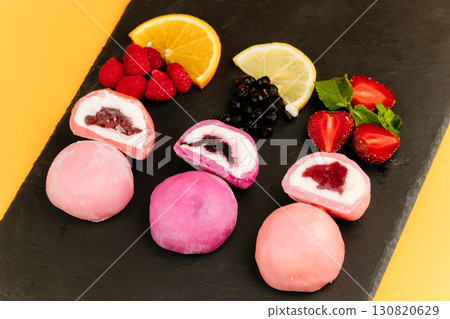 Colorful mochi ice cream with fruity filling on slate board with fresh berries and citrus 130820629