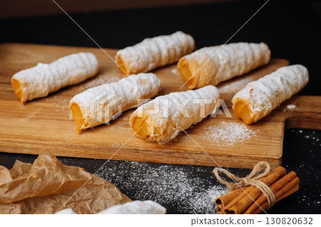 Caramel cream filled pastry rolls dusted with powdered sugar on parchment paper 130820632