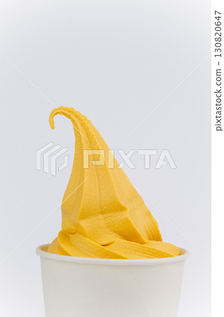 Yellow mango ice cream swirl in white paper cup on clean white background, close up Yellow mango ice cream swirl in white paper cup on clean white background, close up 130820647