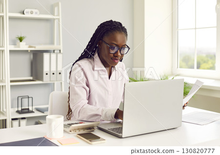 Young African American woman accountant working in office and using laptop computer 130820777