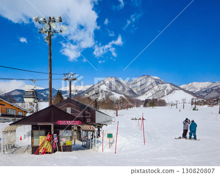 A ski resort under the blue sky and snowboarders in front of the lift station (Tsugaike Kogen, Hakuba, Nagano Prefecture) 130820807