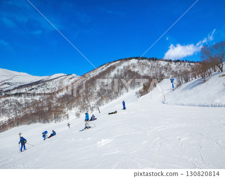 在晴朗的日子裡，人們在白雪皚皚的山巒旁的滑雪勝地享受冬季運動（長野縣白馬村櫂池高原） 130820814