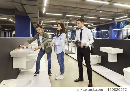 A salesperson in a plumbing store helps a couple choose a sink 130820952