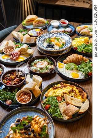 Assorted restaurant style breakfast table with eggs, pastries, salads, and fresh bread 130820984