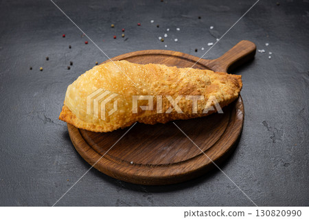 Traditional deep fried cheburek with golden crust served on wooden board, top view 130820990
