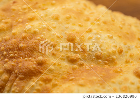 Traditional deep fried cheburek with golden crust served on wooden board, top view 130820996