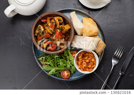 English breakfast with baked beans, ciabatta, and vegetable ragout on black background English breakfast with baked beans, ciabatta, and vegetable ragout on black background 130821016