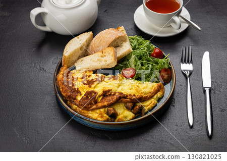 Healthy breakfast with omelet, ciabatta, salad and tea on dark stone background 130821025