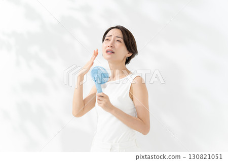 A woman who cools down with a handy fan A woman who cools down with a handy fan 130821051