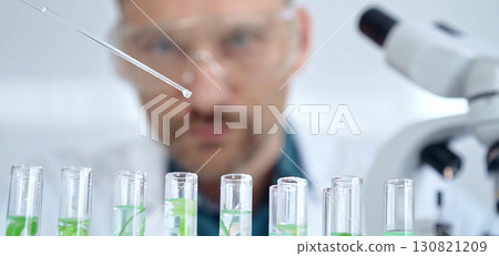 Man researcher with safety glasses is working with lab tubes using a pipette in laboratory, close-up of lab equipment. Science and medicine Man researcher with safety glasses is working with lab tubes using a pipette in laboratory, close-up of lab equipment. Science and medicine 130821209