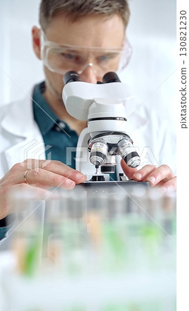 Man scientist with protective glasses using microscope in laboratory. Microbiology science concept Man scientist with protective glasses using microscope in laboratory. Microbiology science concept 130821230