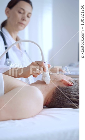 Doctor woman performing neck ultrasound exam on male patient. Medicine service concept Doctor woman performing neck ultrasound exam on male patient. Medicine service concept 130821250