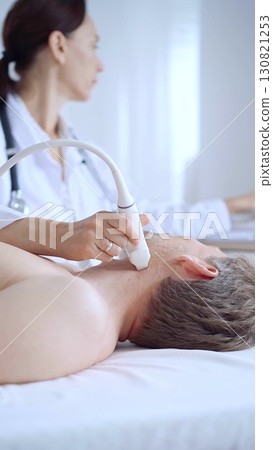 Doctor woman performing neck ultrasound exam on male patient. Medicine service concept 130821253