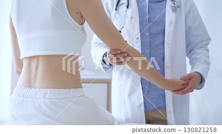 Doctor man examines a patient's elbow during a medical consultat 130821258
