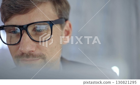 Businessman with glasses looking intently obscured partially by a translucent surface of laptop. Business people concept Businessman with glasses looking intently obscured partially by a translucent surface of laptop. Business people concept 130821295
